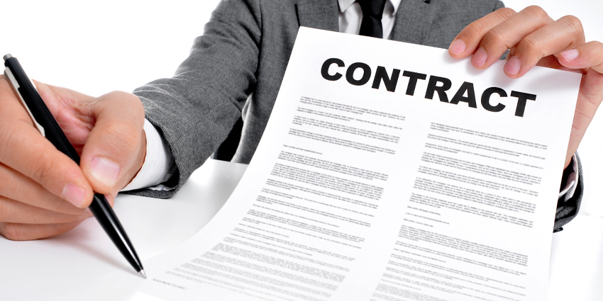 Businessman holding paper with 'Contract' written on it and a pen to camera