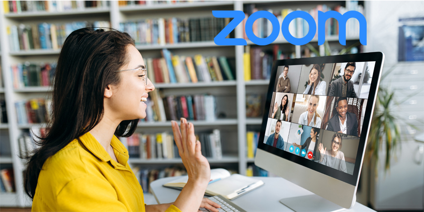 Online education. A female student learning online at home, she waving hand to other students or colleagues on computer monitor in video conference and smiling