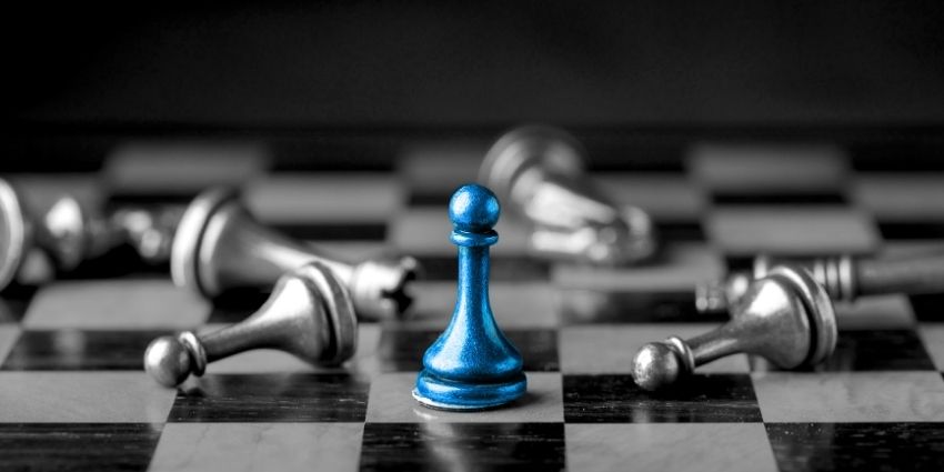 1 chess piece standing amongst many fallen pieces