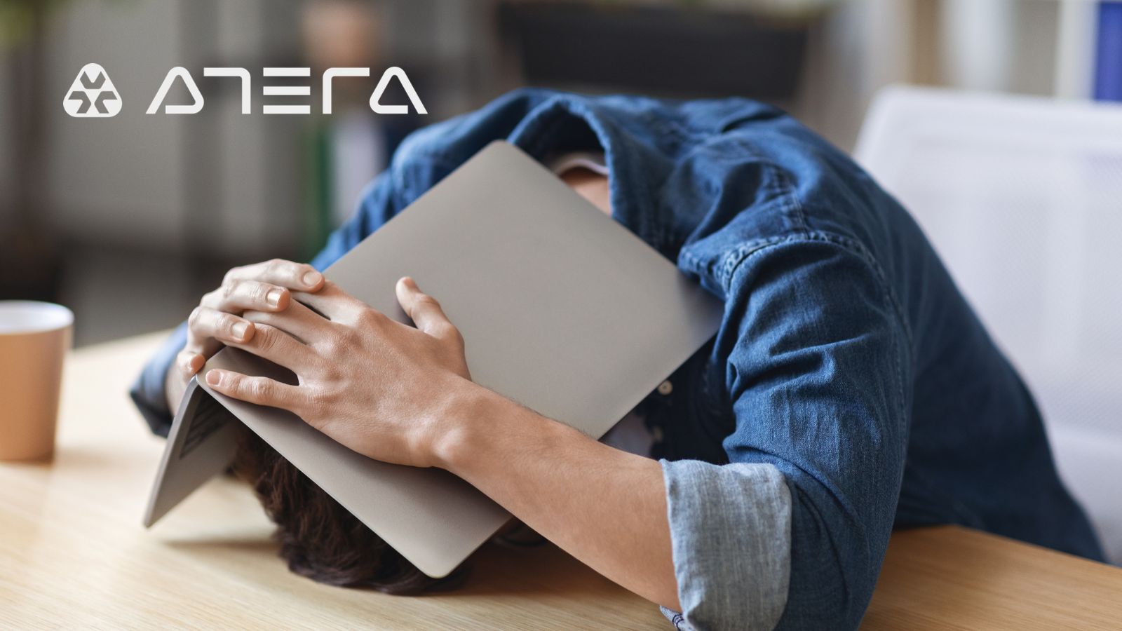 Alt text: A laptop left unattended on a desk with a cold coffee cup, representing the hidden IT friction tax addressed by Atera's service management platform
